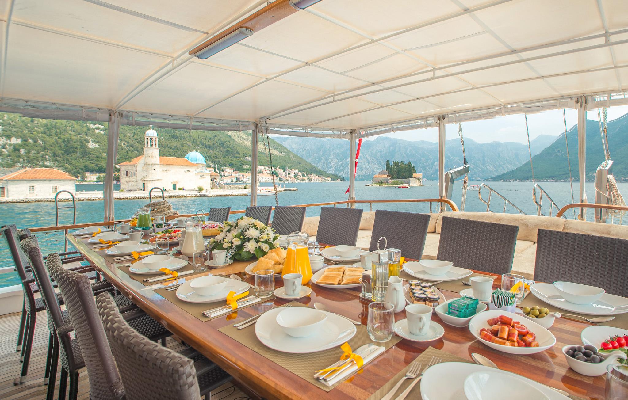 luxury gulet aft deck dining table set with full breakfast spread overlooking Bay of Kotor Montenegro