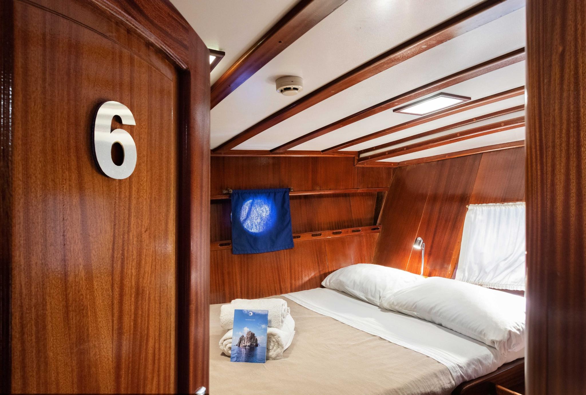 guest cabin number 6 with double bed, white linens, and warm wood paneling