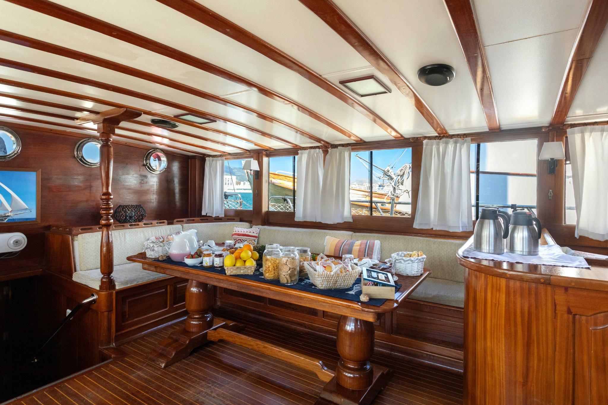 yacht dining table with breakfast spread including fresh fruit, pastries, coffee service and table settings