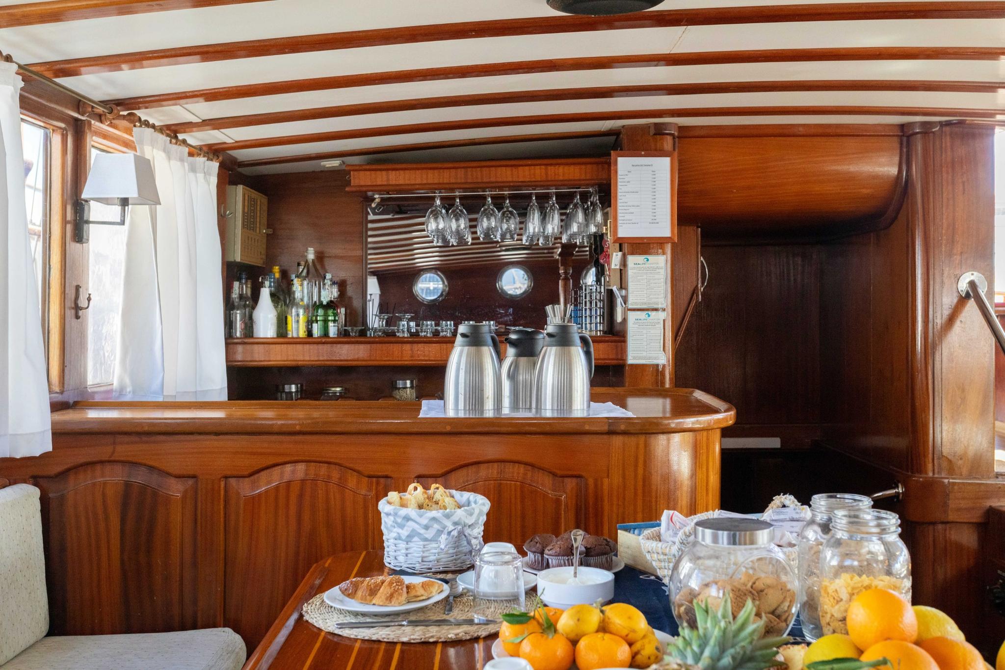 yacht galley breakfast spread with oranges, pastries, and beverages on wooden counter