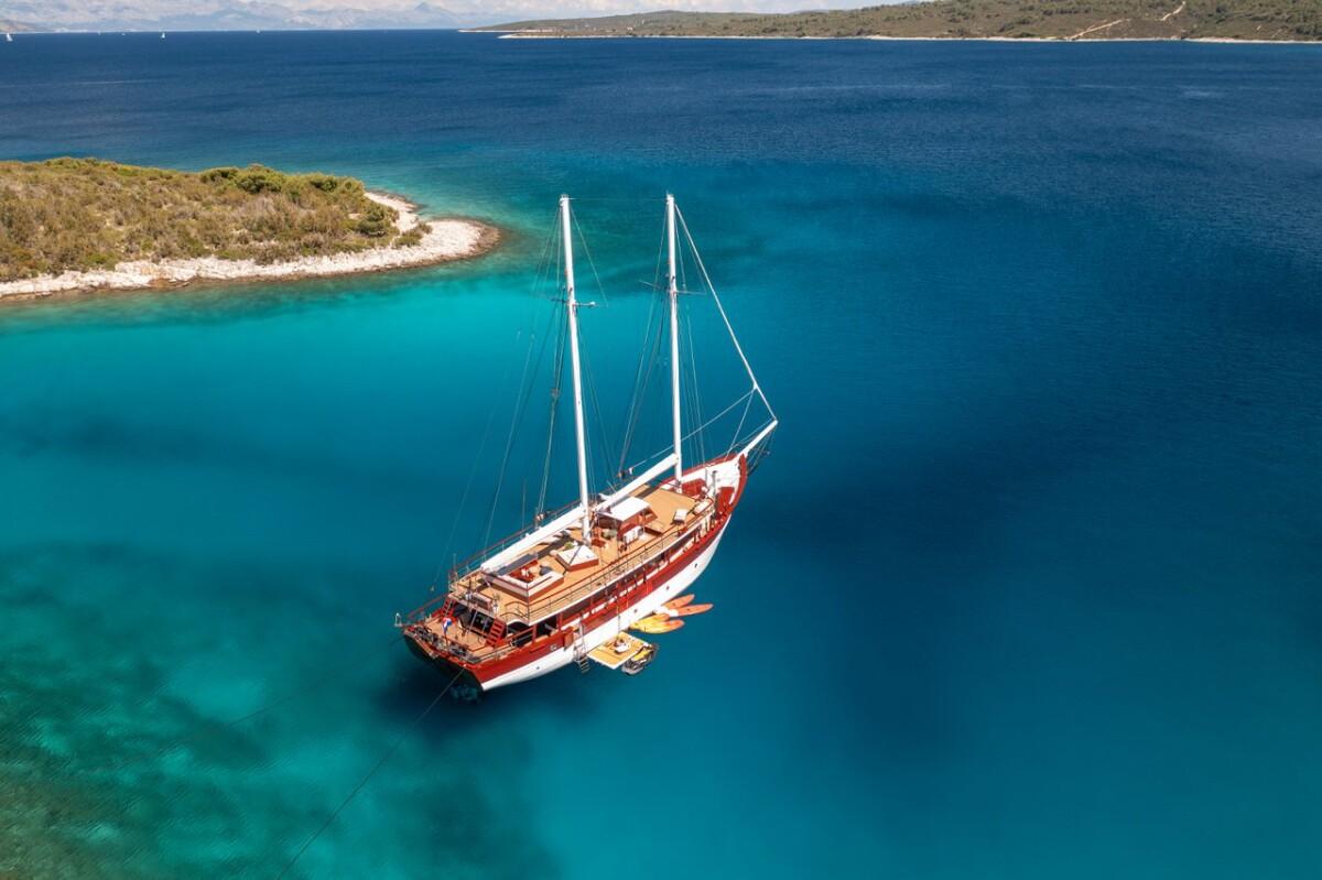 Luxury wooden gulet yacht anchored in crystal clear turquoise Mediterranean waters