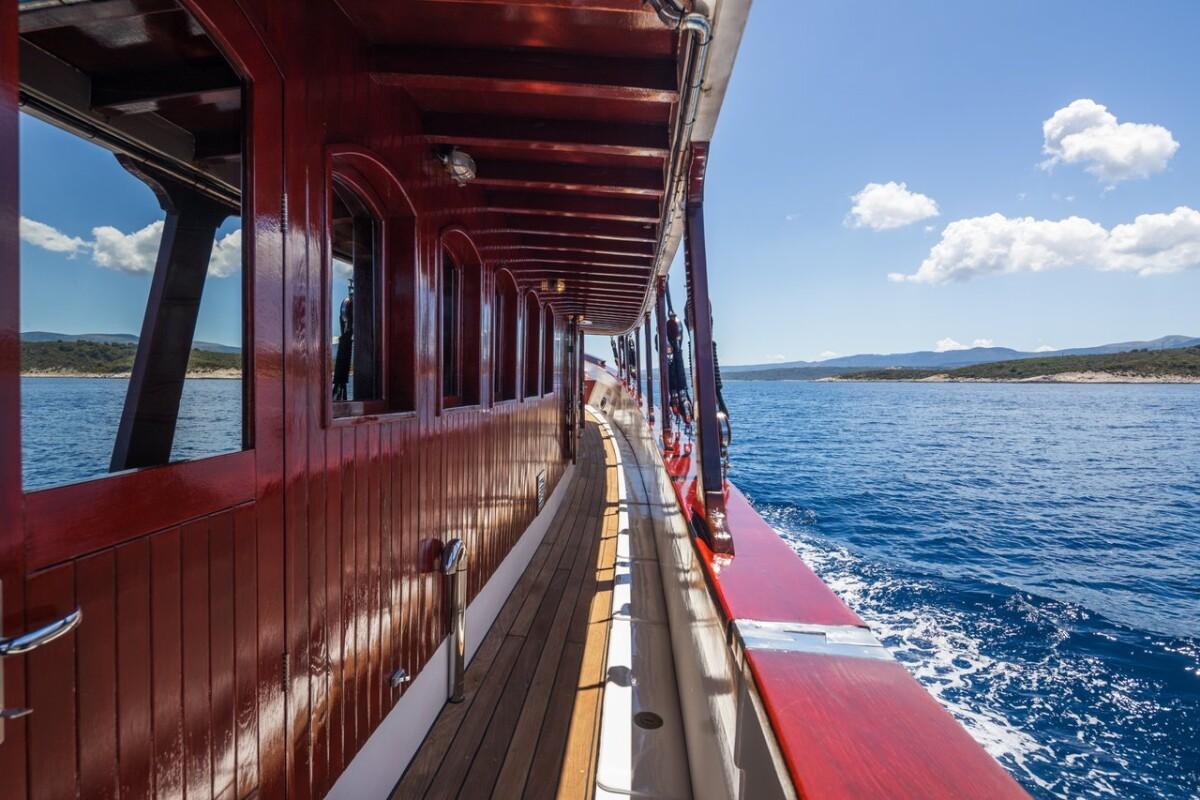 yacht side deck promenade with wooden paneling and arched windows while cruising