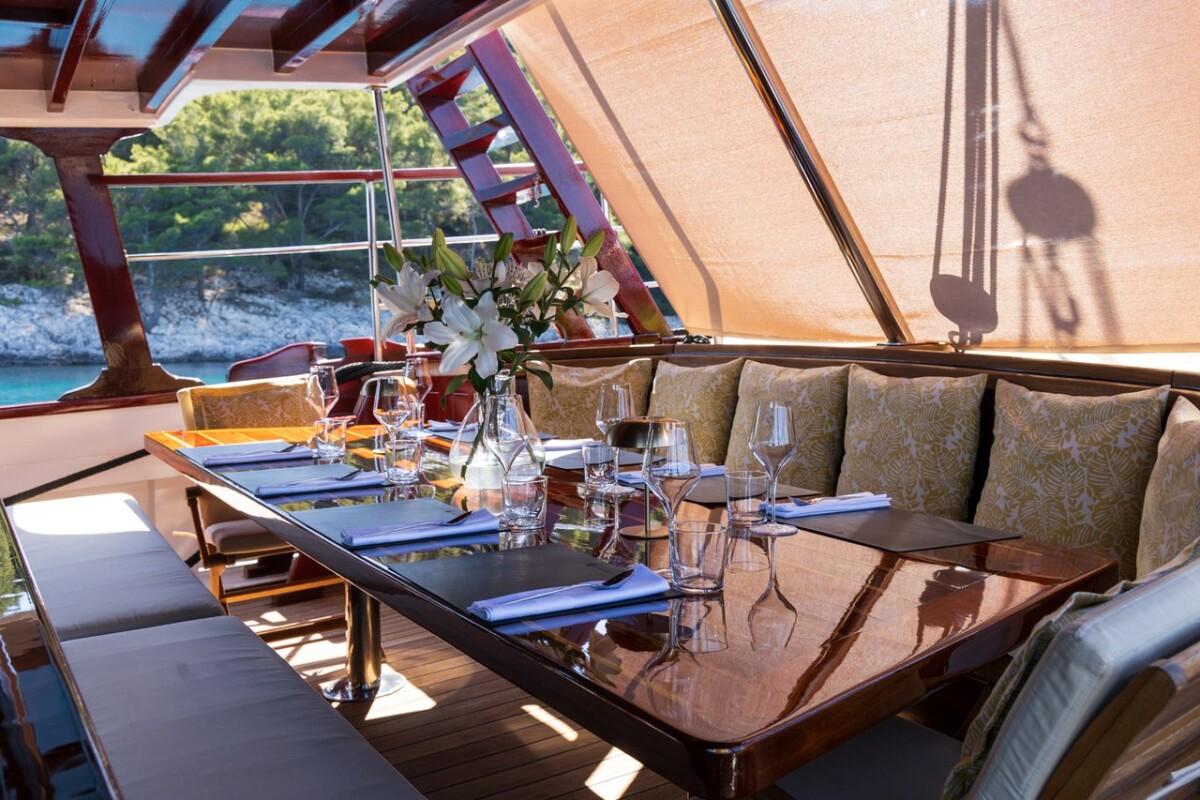 luxury yacht outdoor dining area with formal table setting and coastal views