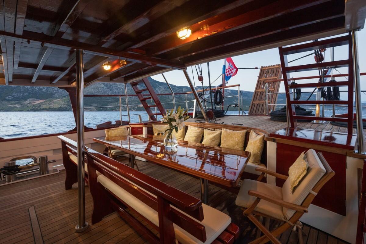 Traditional gulet aft deck dining area with wooden table and cushioned seating