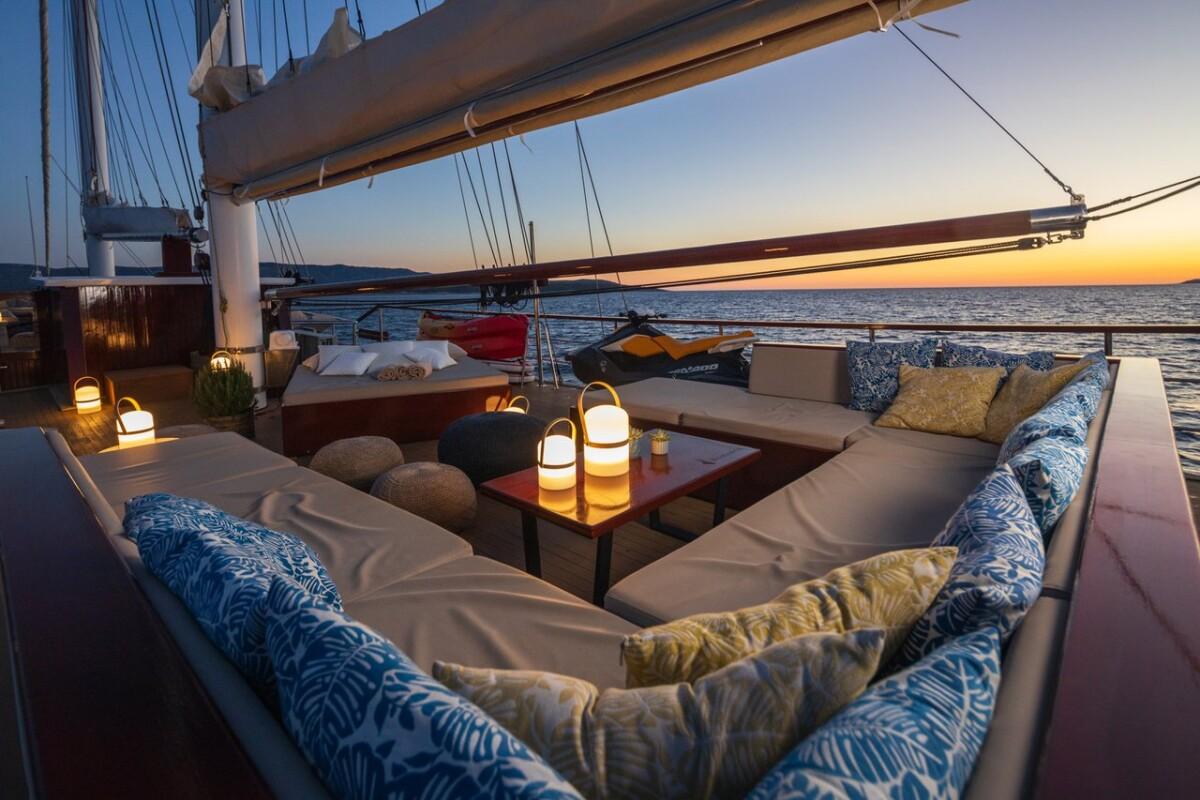 Luxury yacht deck seating with glowing lanterns at sunset over ocean