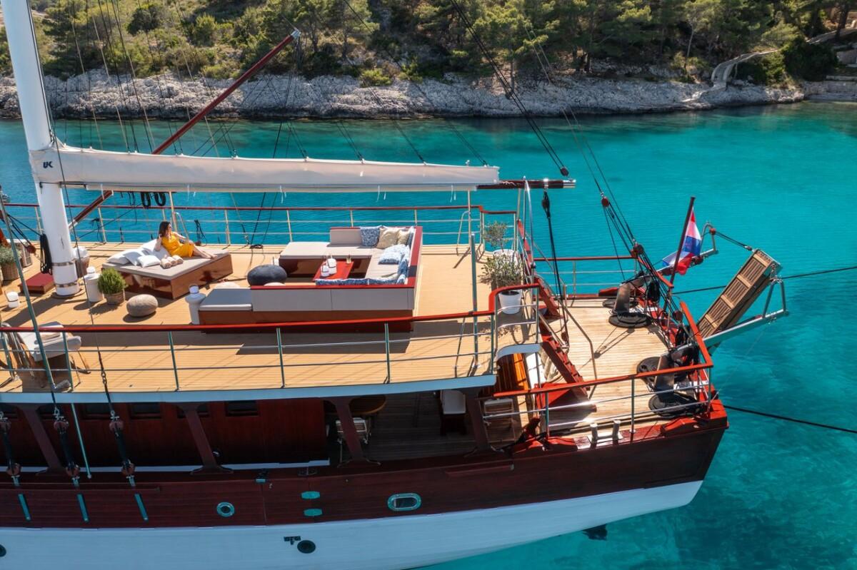 luxury wooden gulet yacht with sunbed deck anchored in turquoise bay
