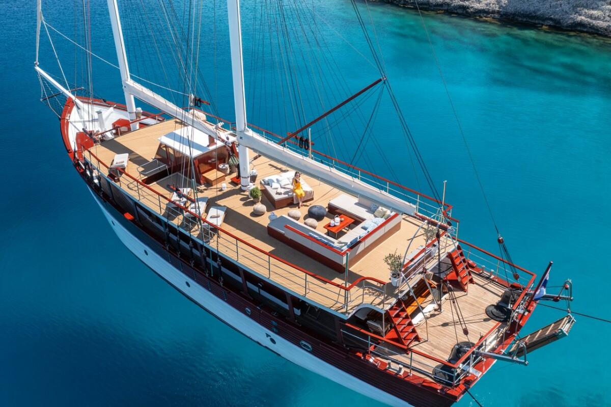 Aerial view luxury gulet yacht white hull red trim anchored crystal clear waters
