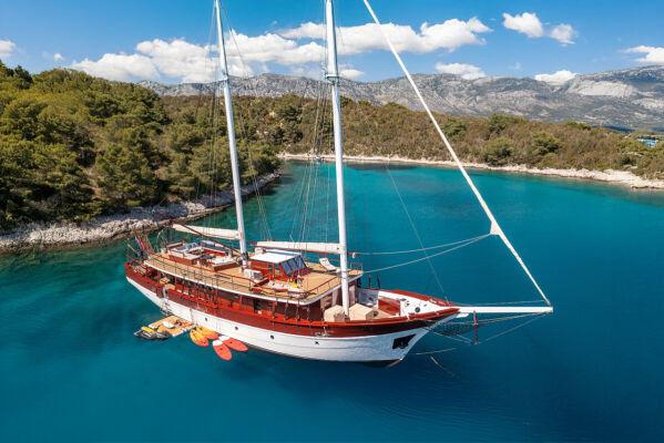 Luxury wooden gulet yacht anchored in crystal clear turquoise Mediterranean bay