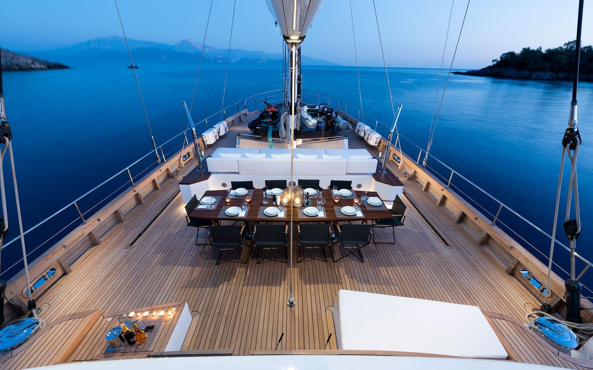 gulet main deck with formal dining table set for eight guests at sunset