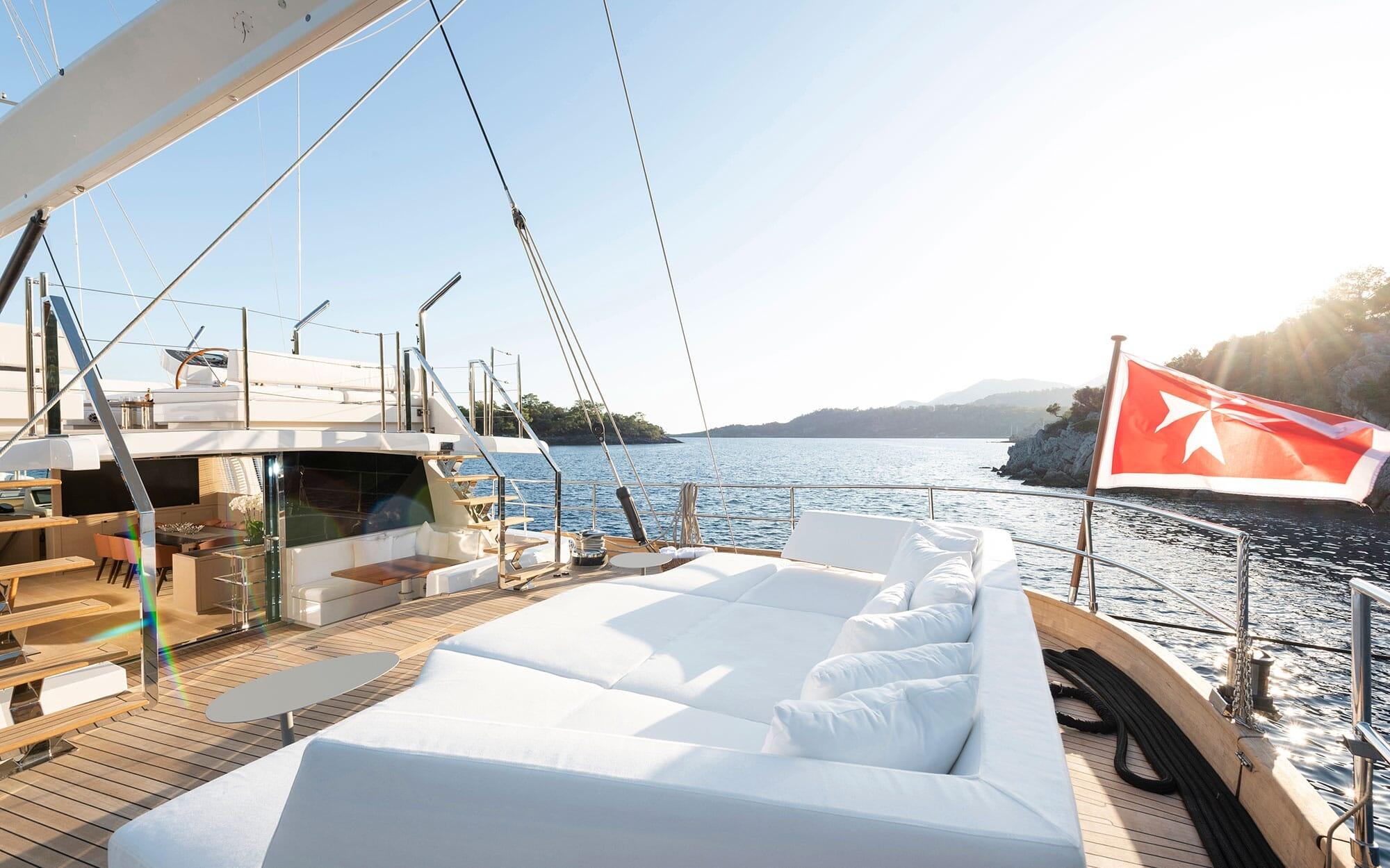 luxury gulet foredeck with white cushioned sun loungers and Turkish flag flying