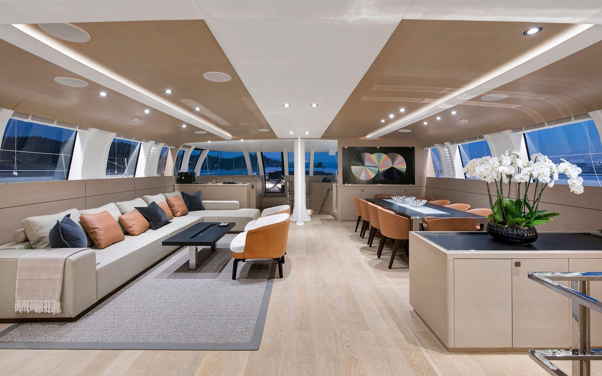 luxury yacht main salon with white sectional sofa, orange dining chairs, and panoramic windows