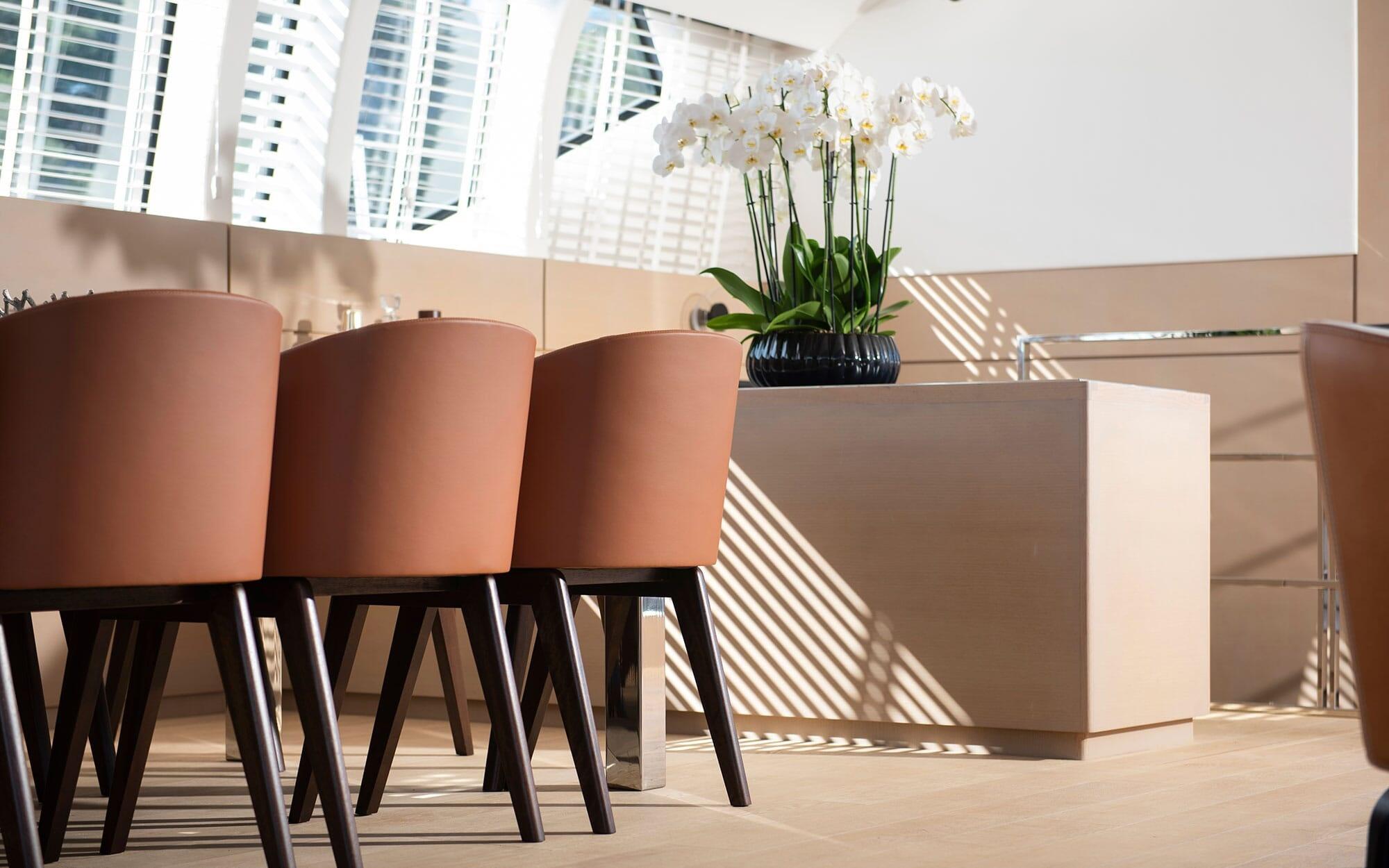yacht interior dining area with tan upholstered chairs and white orchid arrangement