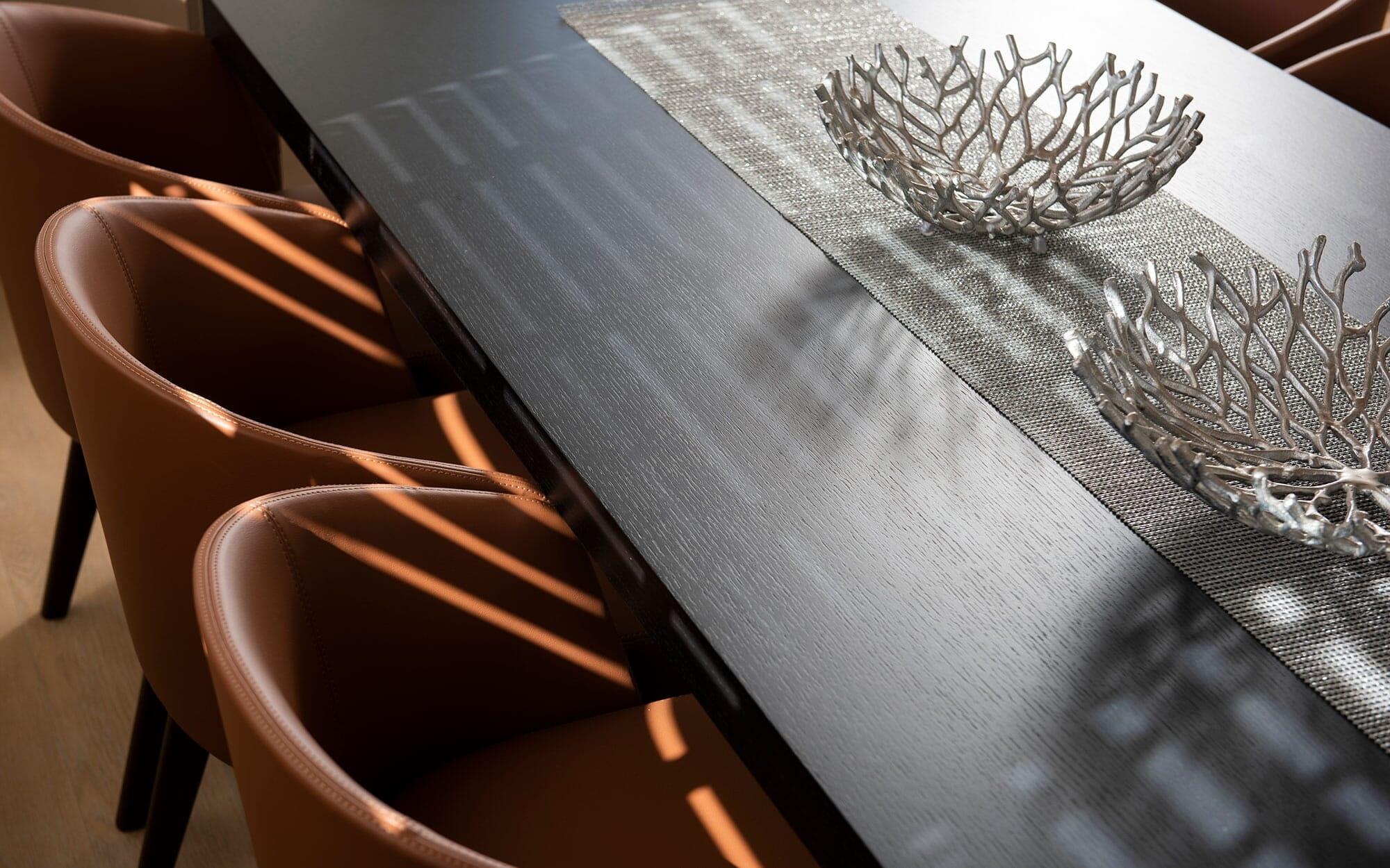 yacht dining area with dark wood table, decorative coral bowls and tan leather chairs