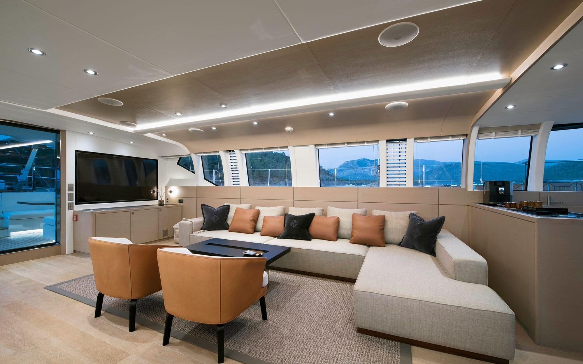 luxury yacht main salon with wraparound sectional sofa, wall-mounted TV, and panoramic windows