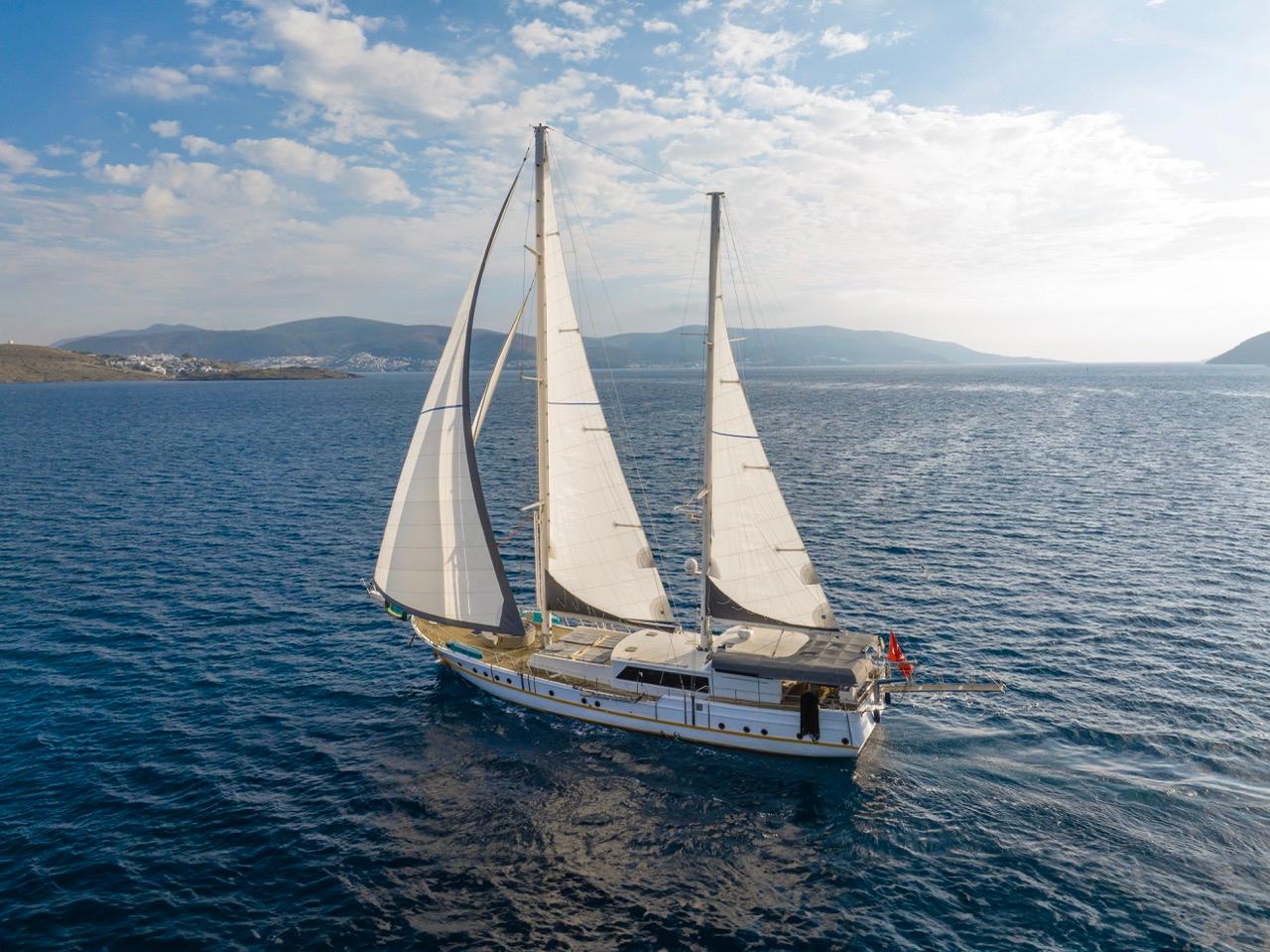 traditional wooden sailing gulet with white sails deployed cruising blue Mediterranean waters