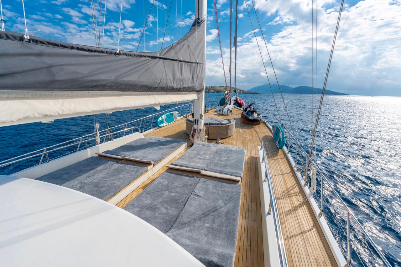 gulet bow deck with grey sunbathing cushions, teak decking and sailing rigging