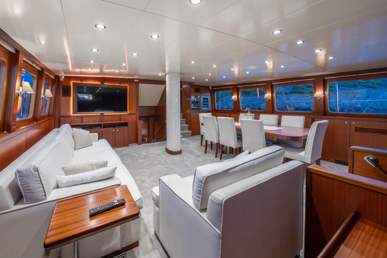 luxury yacht cinema room with large wall-mounted screen, white leather seating and dining table