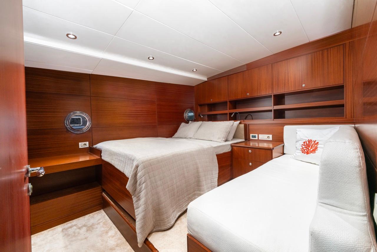 yacht guest cabin with two single beds, mahogany paneling and built-in storage