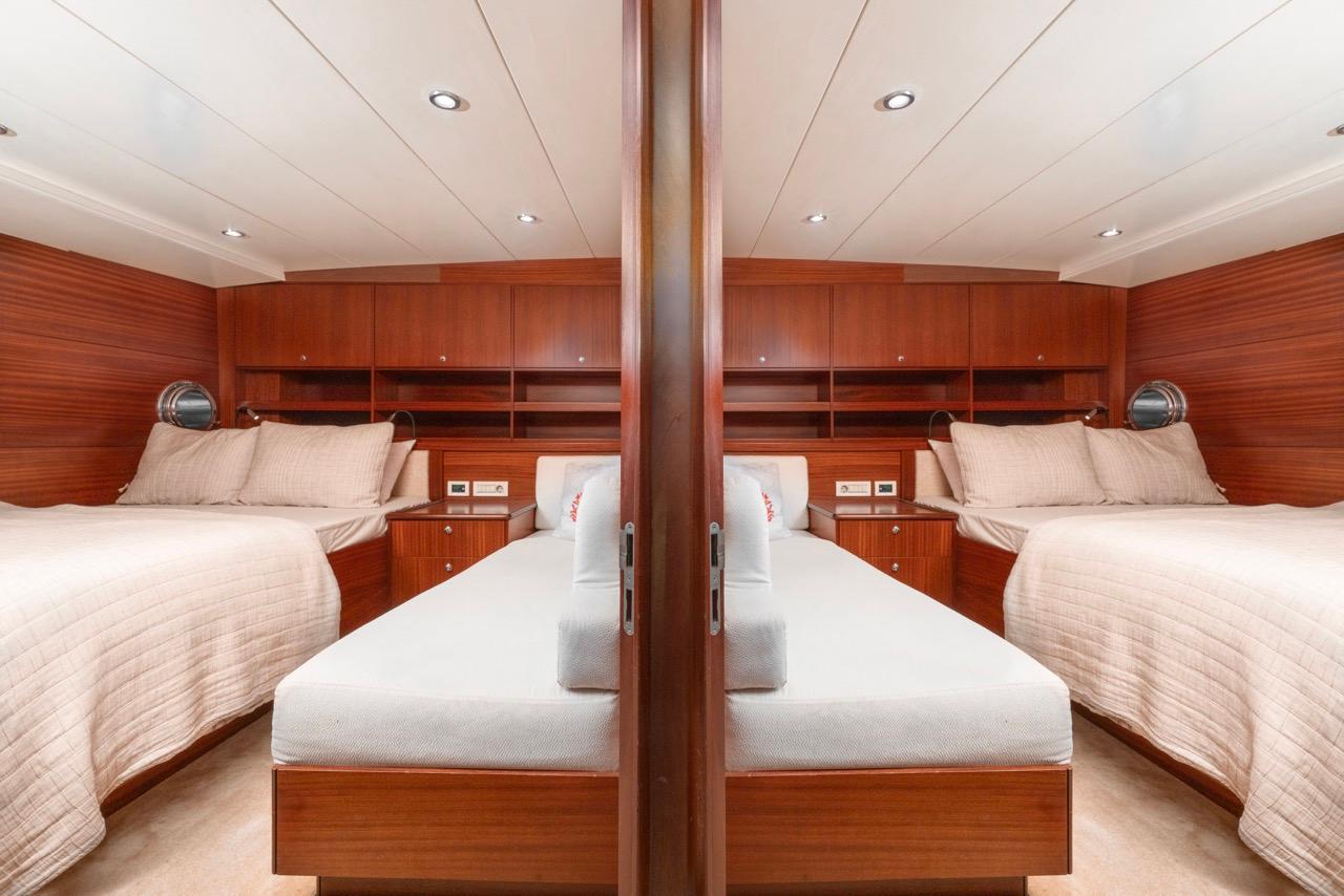 yacht twin cabin with two single beds, rich wood paneling and overhead storage compartments