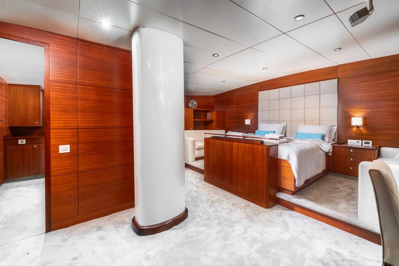 luxury yacht master cabin featuring king bed with white bedding and marble flooring