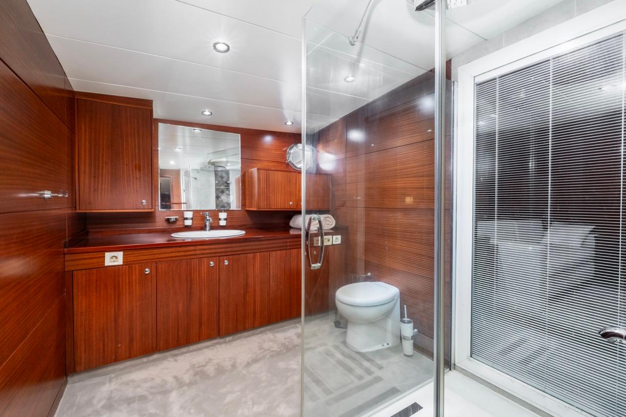 luxury yacht bathroom with glass shower enclosure, wood vanity unit and white toilet