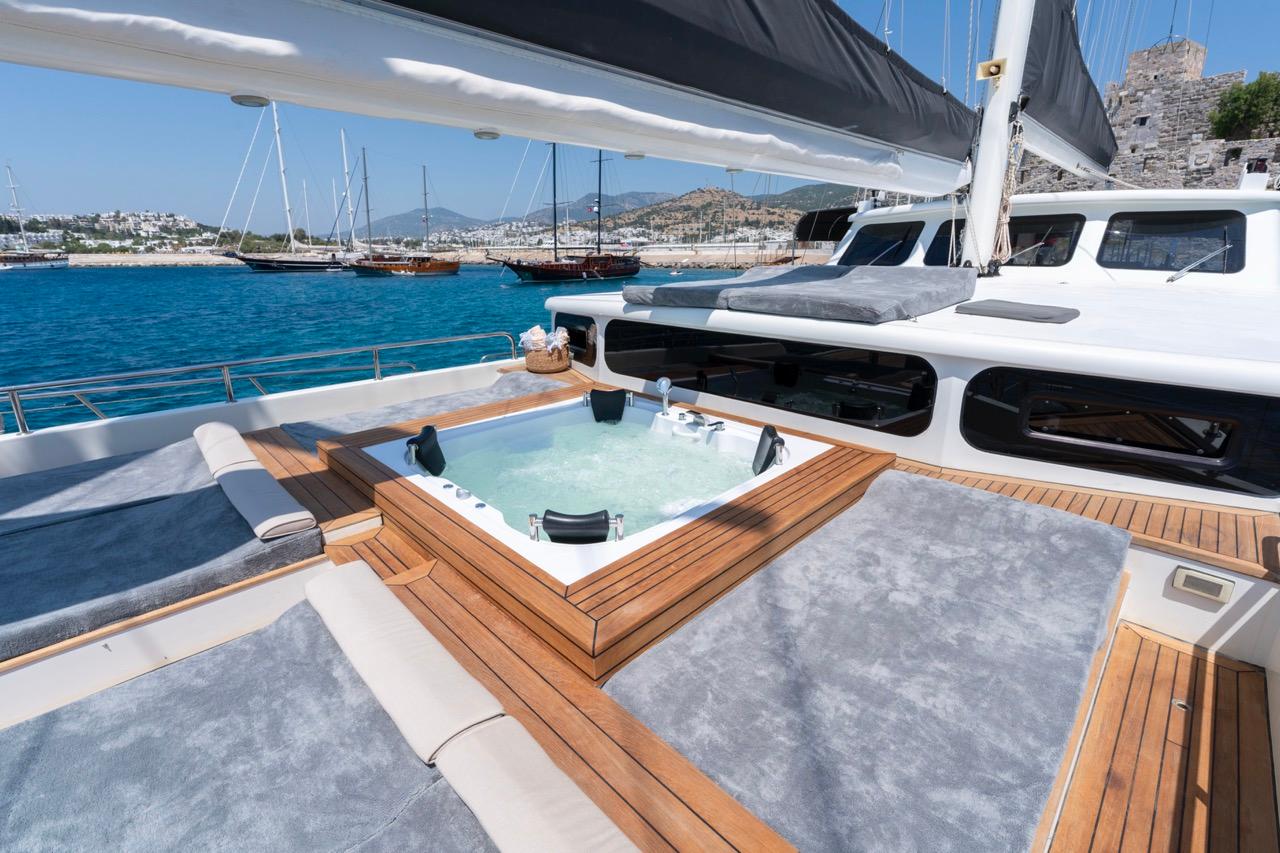 yacht deck jacuzzi with teak wood surround and gray cushioned seating areas