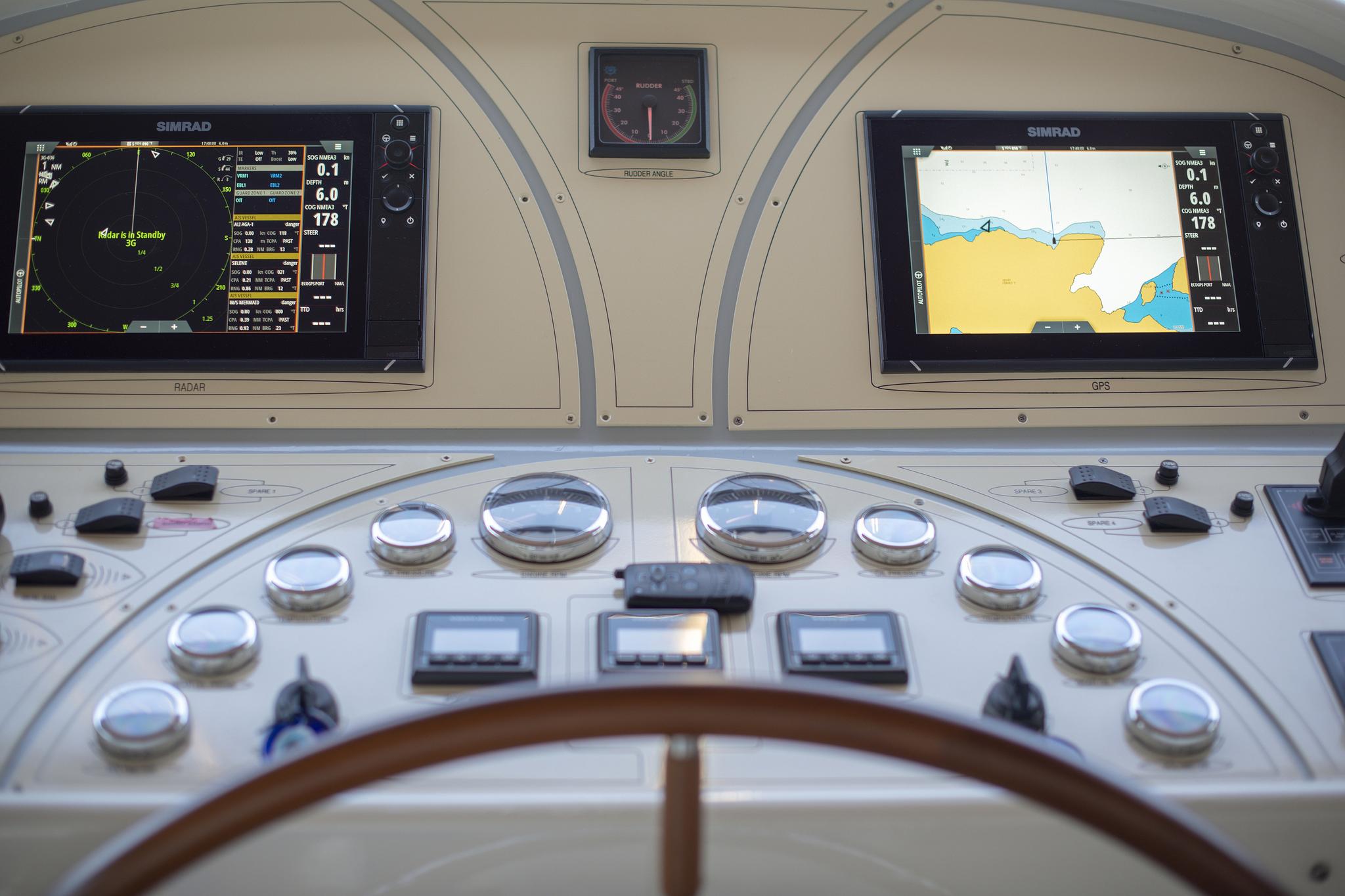 yacht helm station with dual Simrad displays showing radar and GPS navigation charts