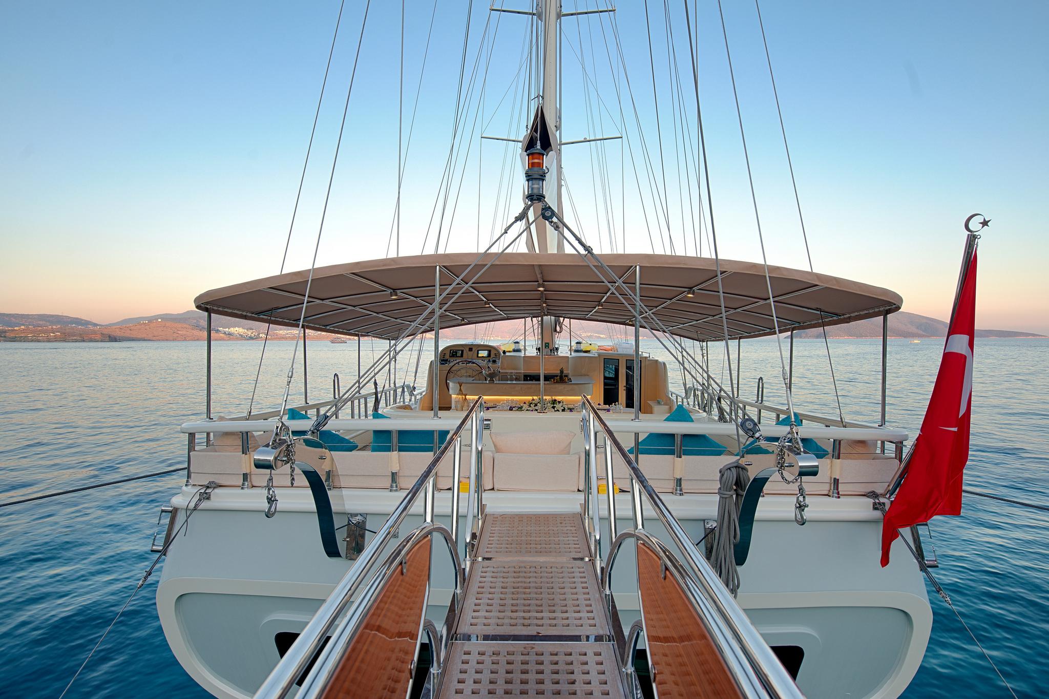 gulet aft deck with built-in seating, stairs, bimini shade canopy and Turkish flag