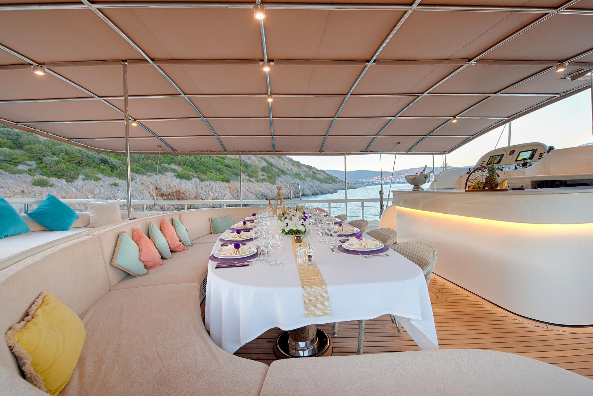 yacht aft deck dining area with formal table settings and coastal views