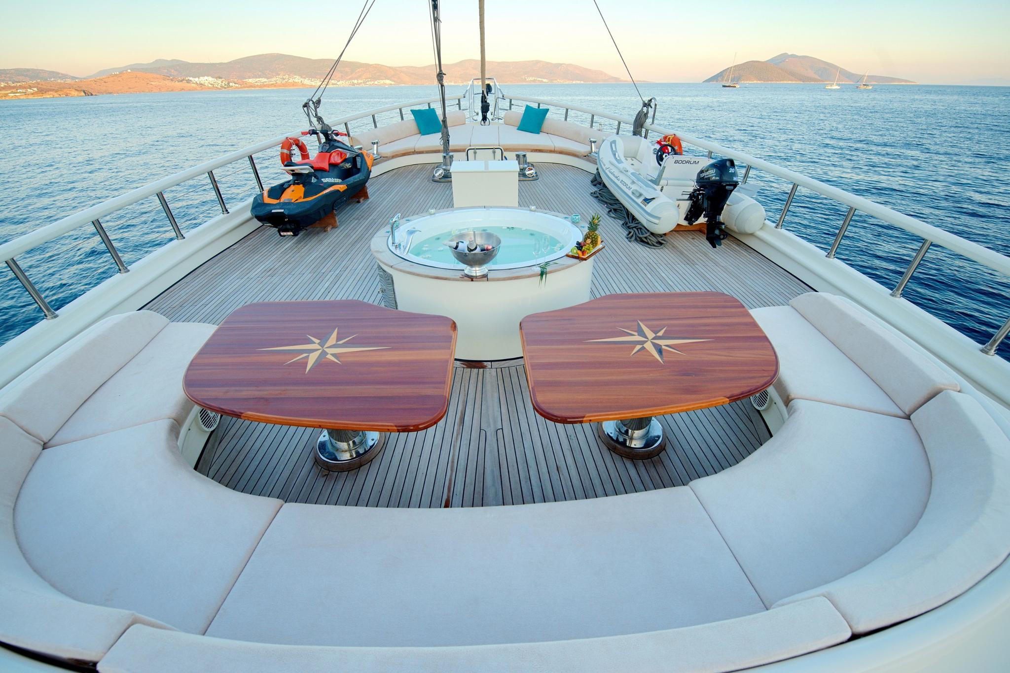 yacht upper deck with round jacuzzi, jet ski, tender boat and curved seating area