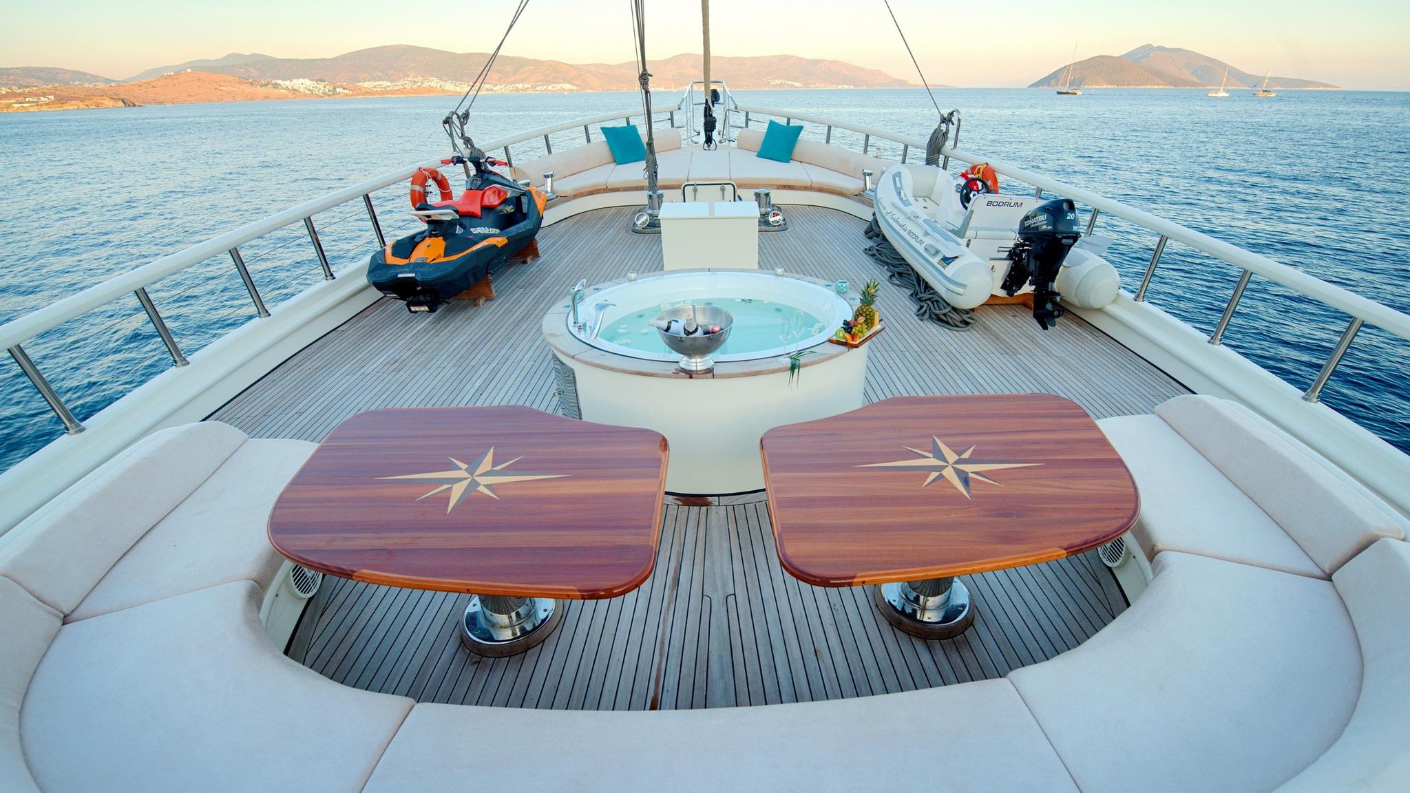 luxury yacht upper deck featuring round jacuzzi, jet ski, tender boat and dining tables