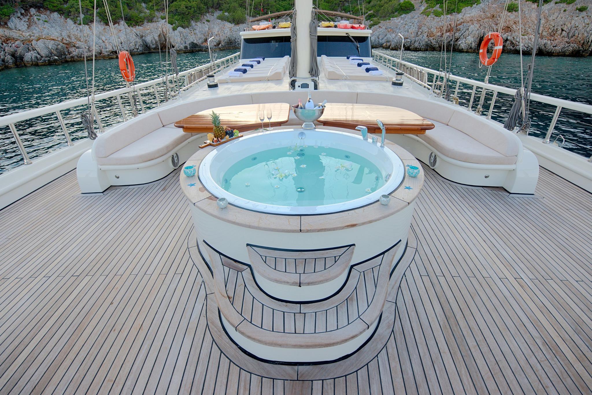 circular jacuzzi with turquoise water on yacht foredeck surrounded by curved white seating