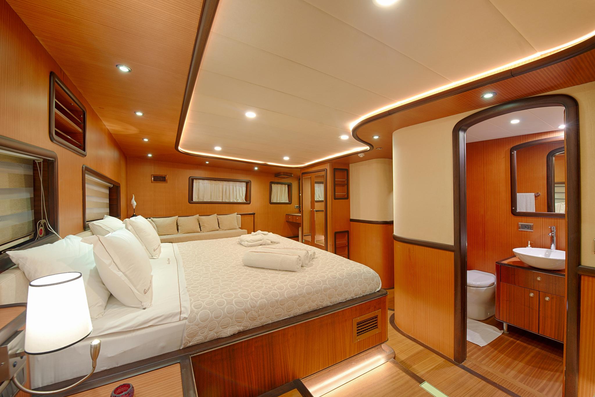 luxury yacht master cabin featuring double bed, teak flooring, and open en-suite bathroom