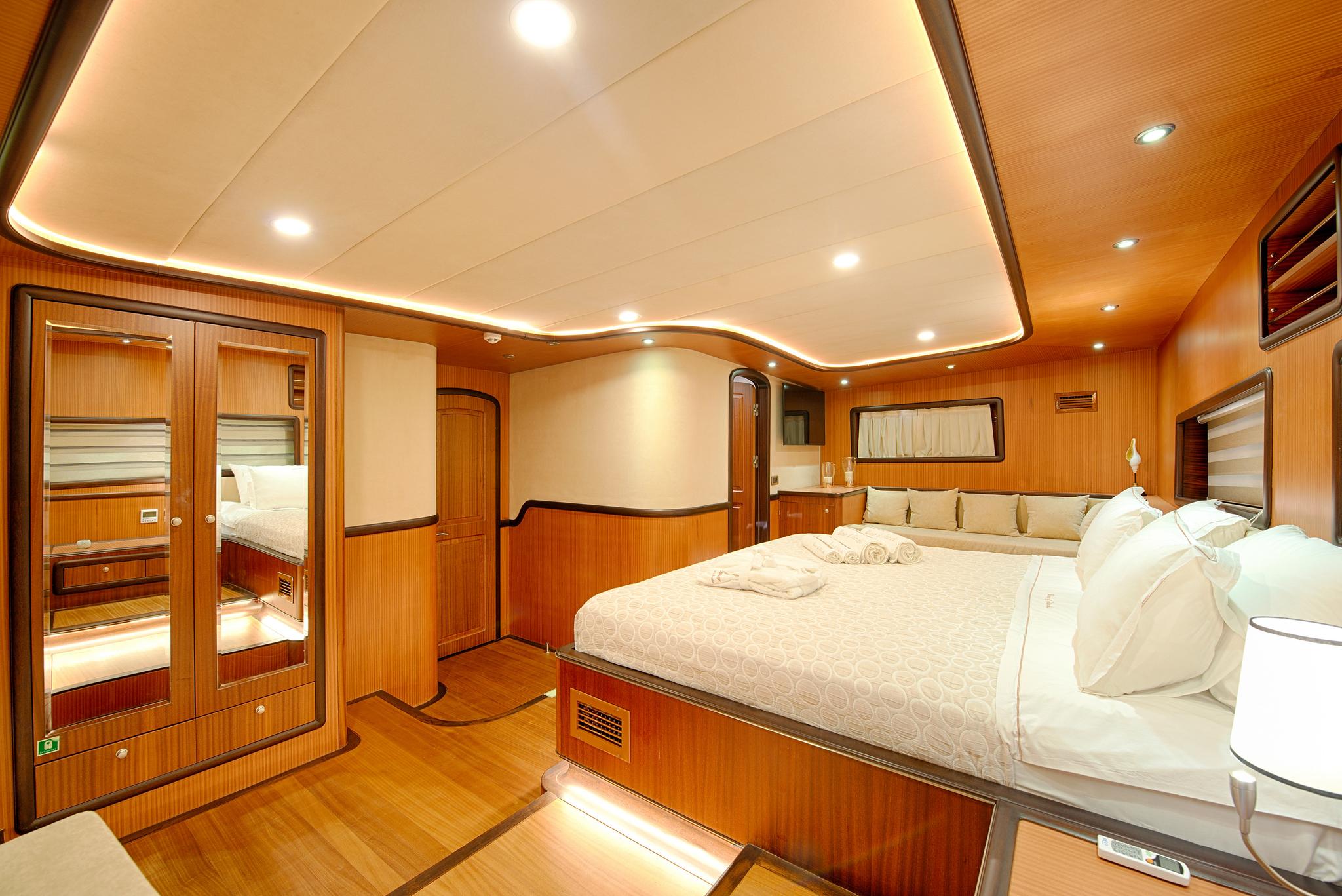 spacious yacht master cabin featuring king bed with white linens and teak wood paneling