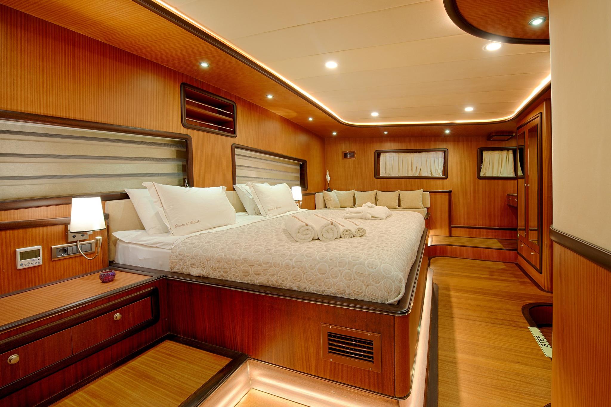 spacious master cabin featuring double bed with white linens and curved seating area