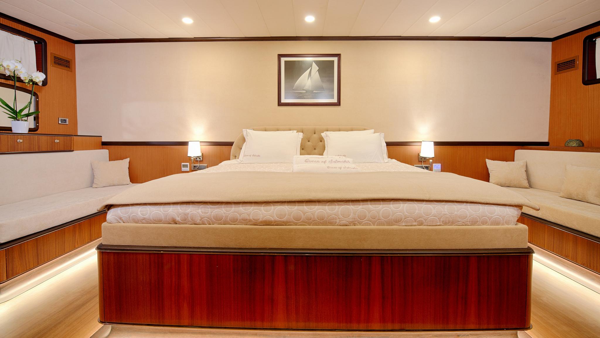 yacht master cabin featuring king bed with beige linens and built-in side seating