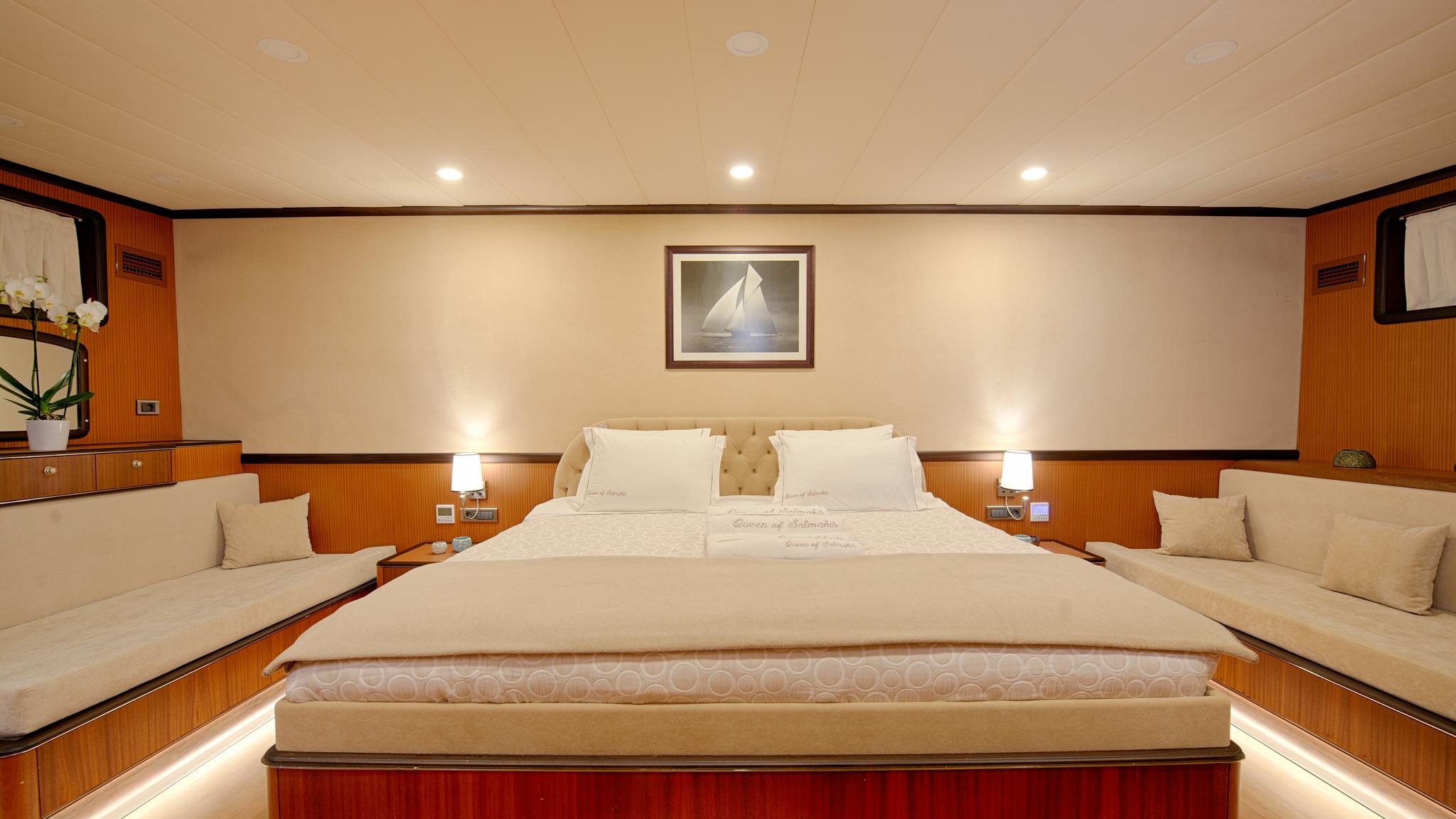 luxury yacht master cabin featuring king bed with white linens, built-in side seating, and nautical artwork