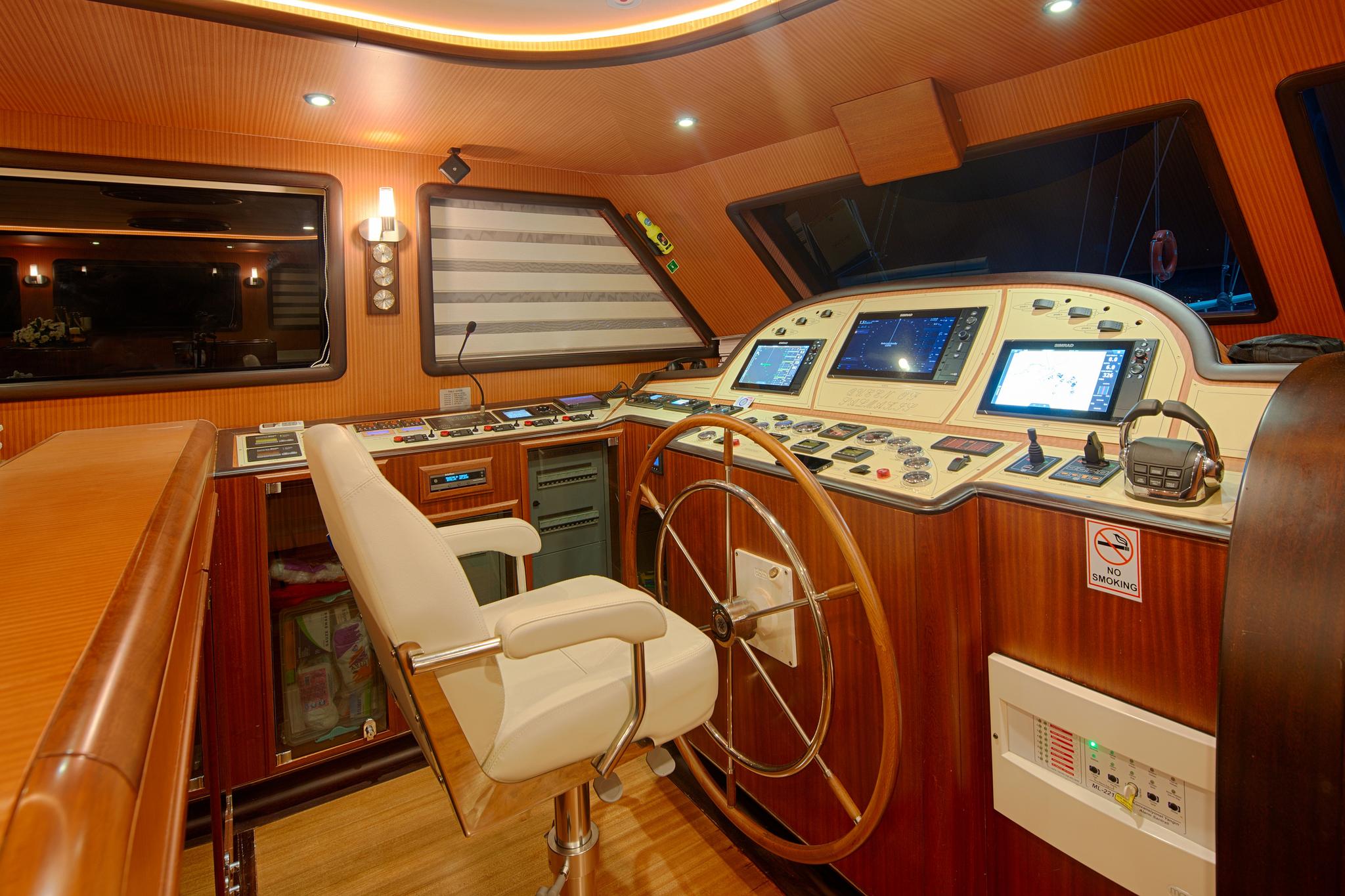 luxury yacht wheelhouse with multiple navigation screens, wooden steering wheel and captain's chair