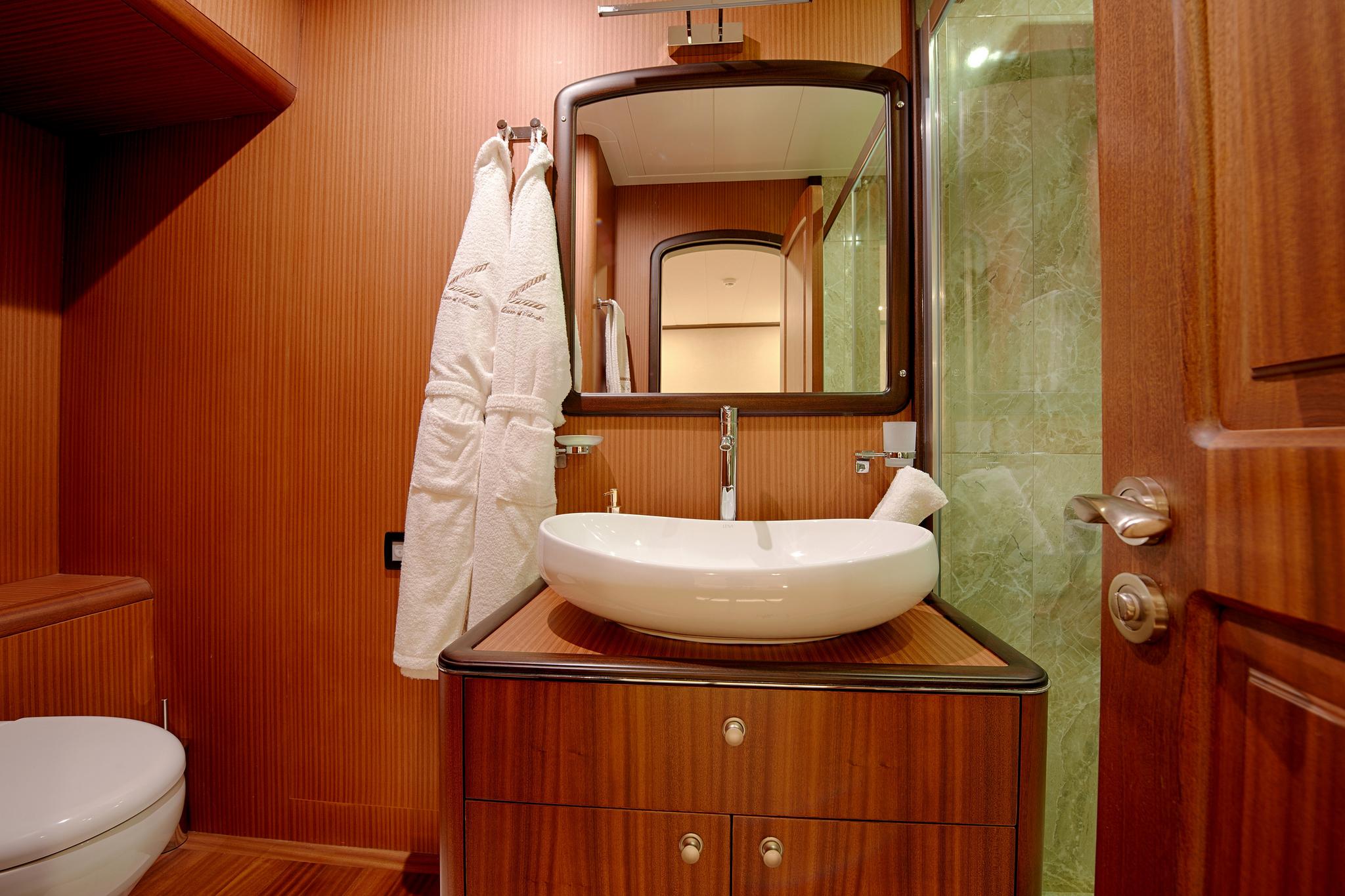 yacht bathroom featuring white vessel sink on wooden vanity with mirror