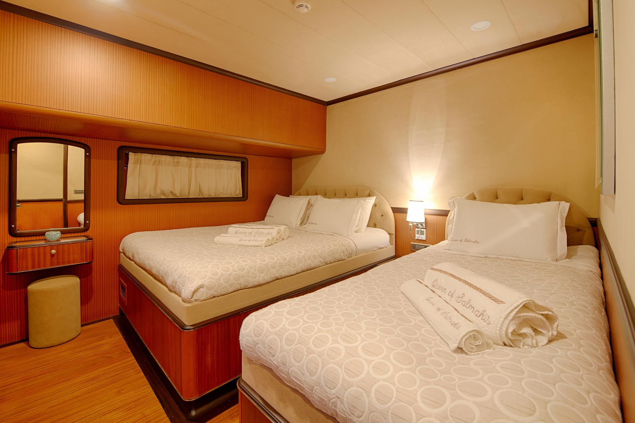 yacht twin cabin with two single beds, wooden vanity with mirror and recessed lighting