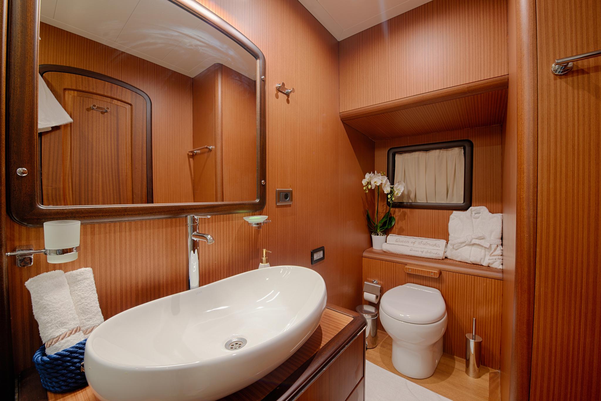 yacht bathroom interior with white oval basin sink, toilet, and wood paneling