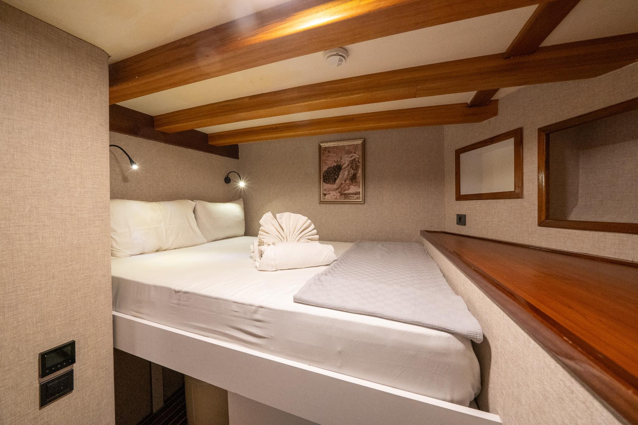 yacht guest cabin featuring double bed with white linens and exposed wooden ceiling beams
