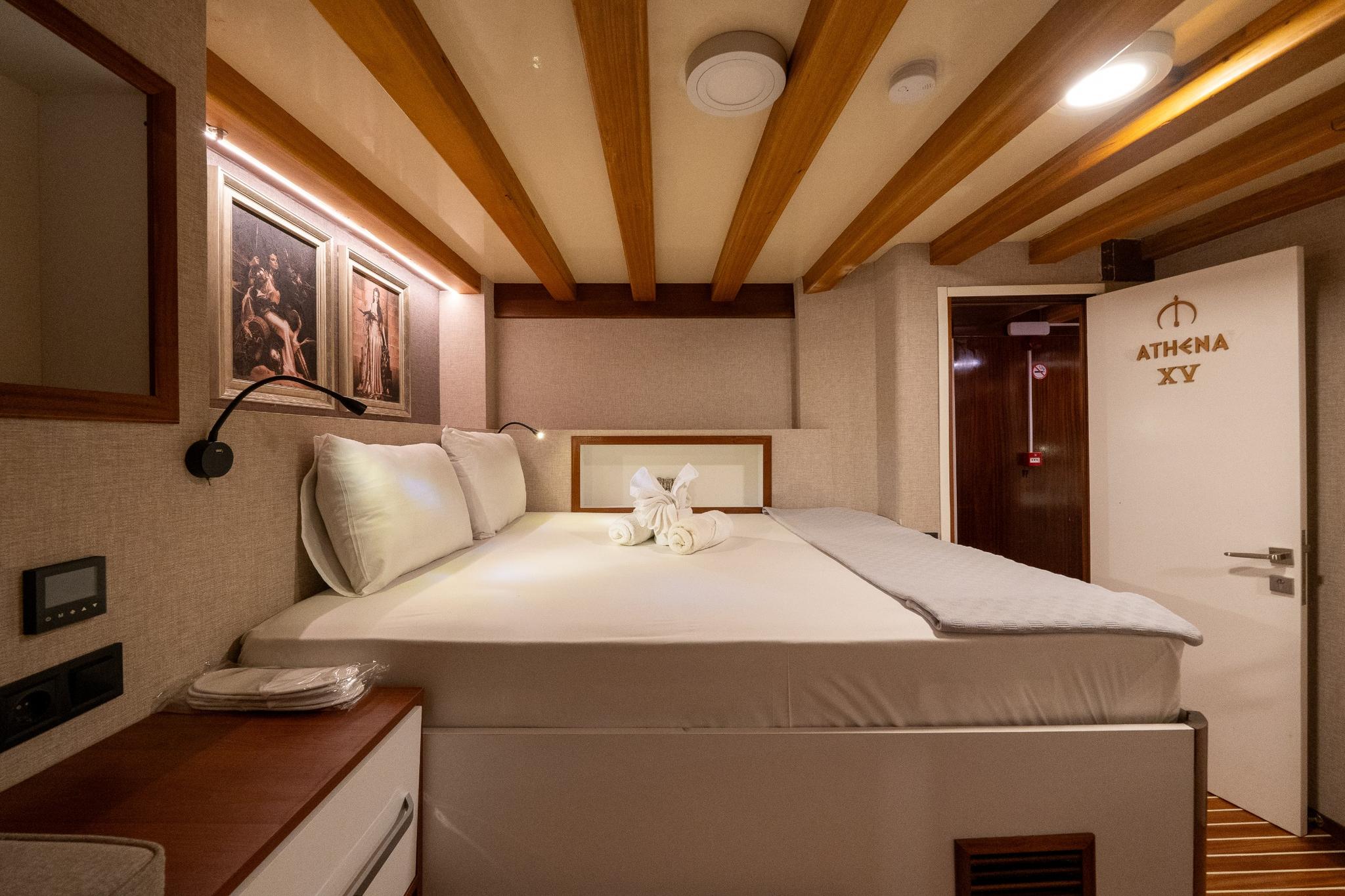 yacht guest cabin featuring double bed, exposed wooden ceiling beams, and towel arrangement
