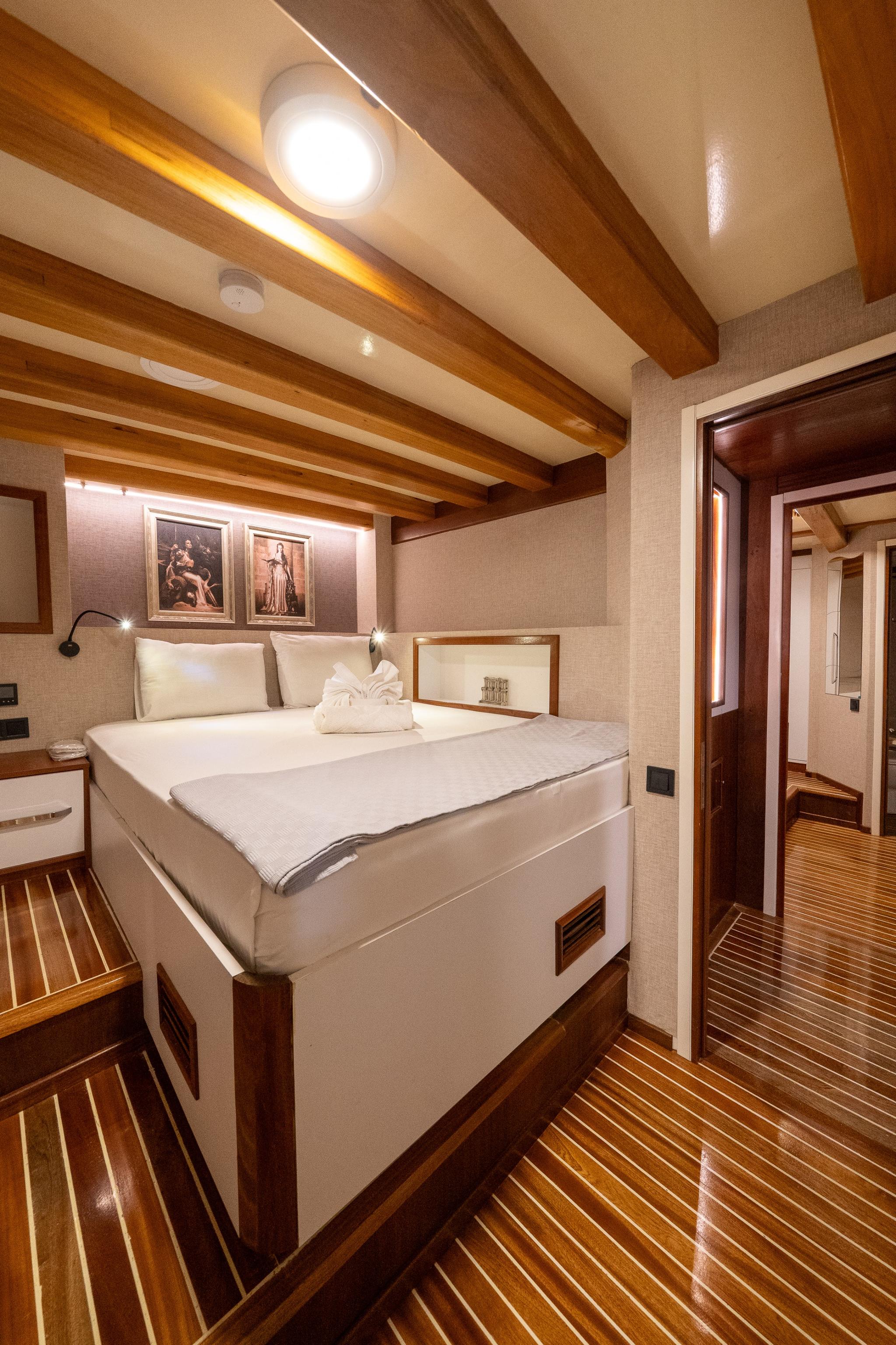 yacht guest cabin featuring double bed, exposed wooden ceiling beams, and nautical artwork