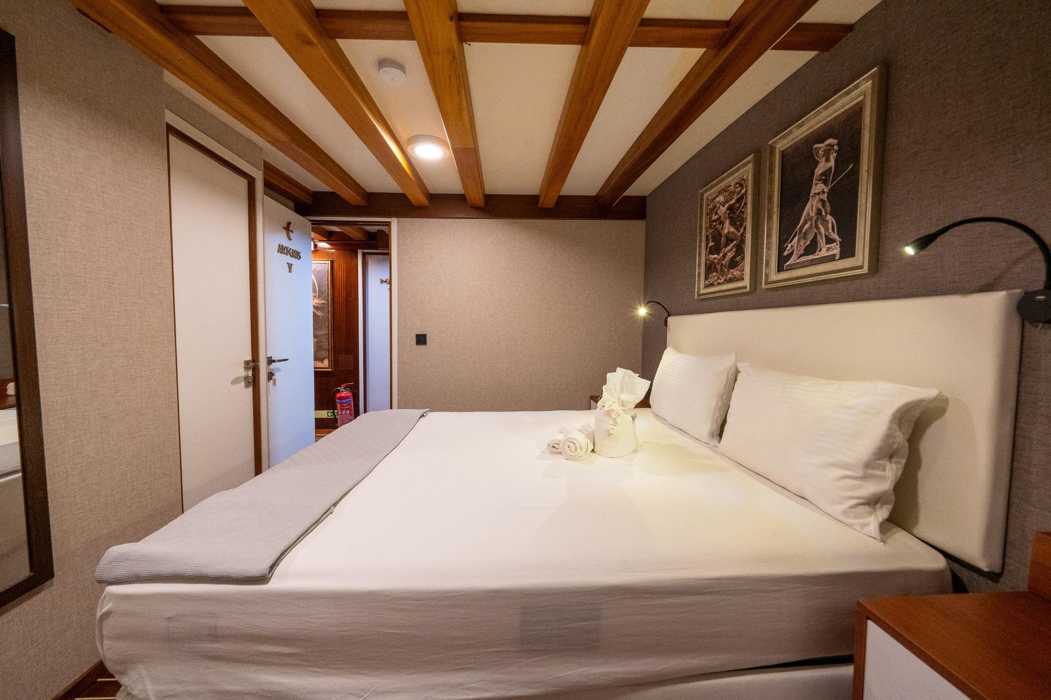 yacht guest cabin featuring double bed with white linens and wooden beam ceiling