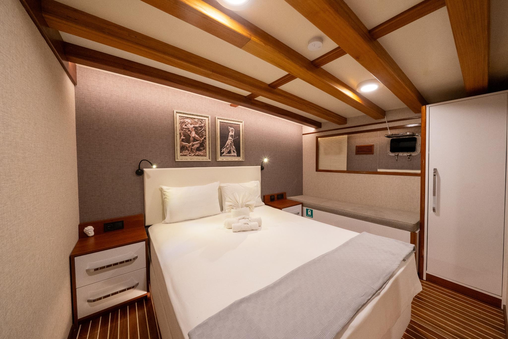 yacht guest cabin featuring double bed, wood beam ceiling, reading lights and built-in wardrobe