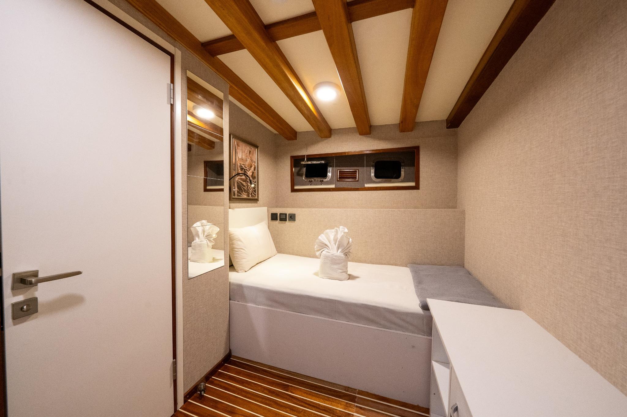 yacht guest cabin featuring twin beds with white linens and exposed wooden ceiling beams