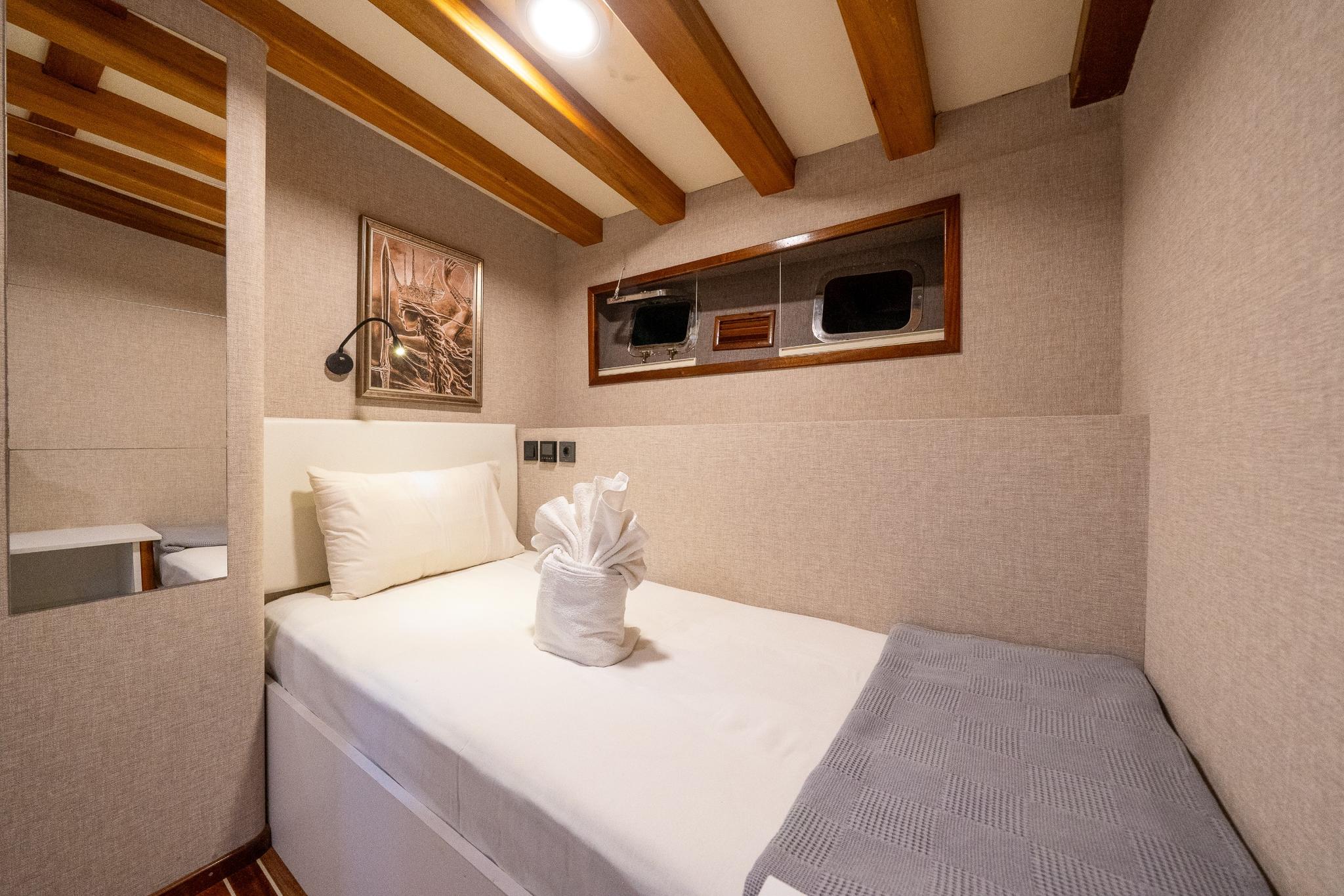 yacht guest cabin featuring single bed with white linens and decorative towel sculpture