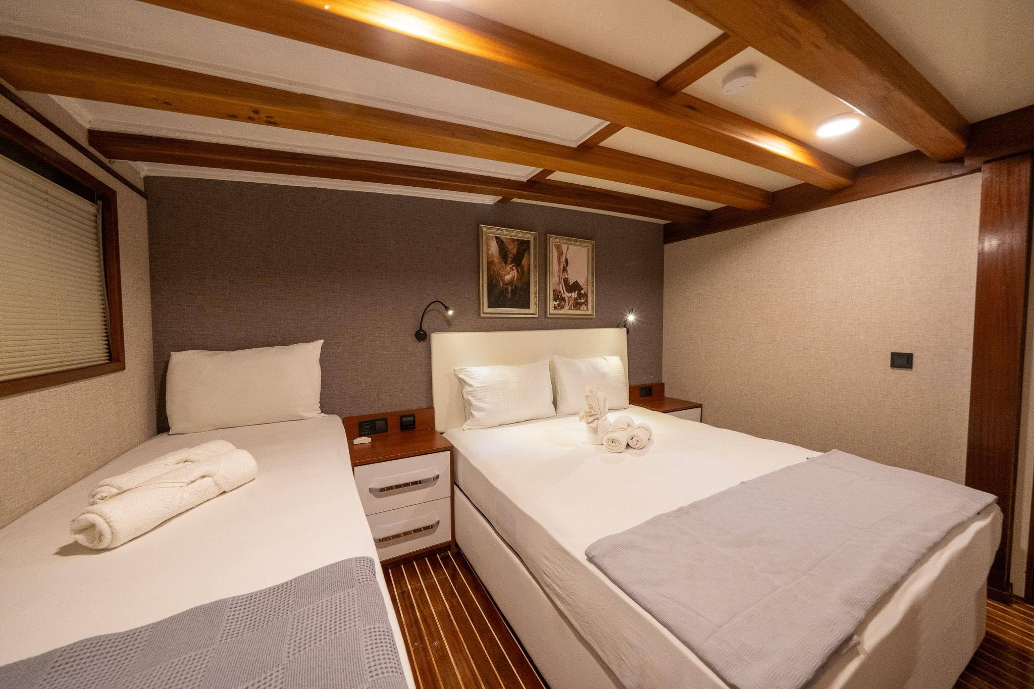 yacht guest cabin featuring twin bed and double bed with exposed wooden ceiling beams