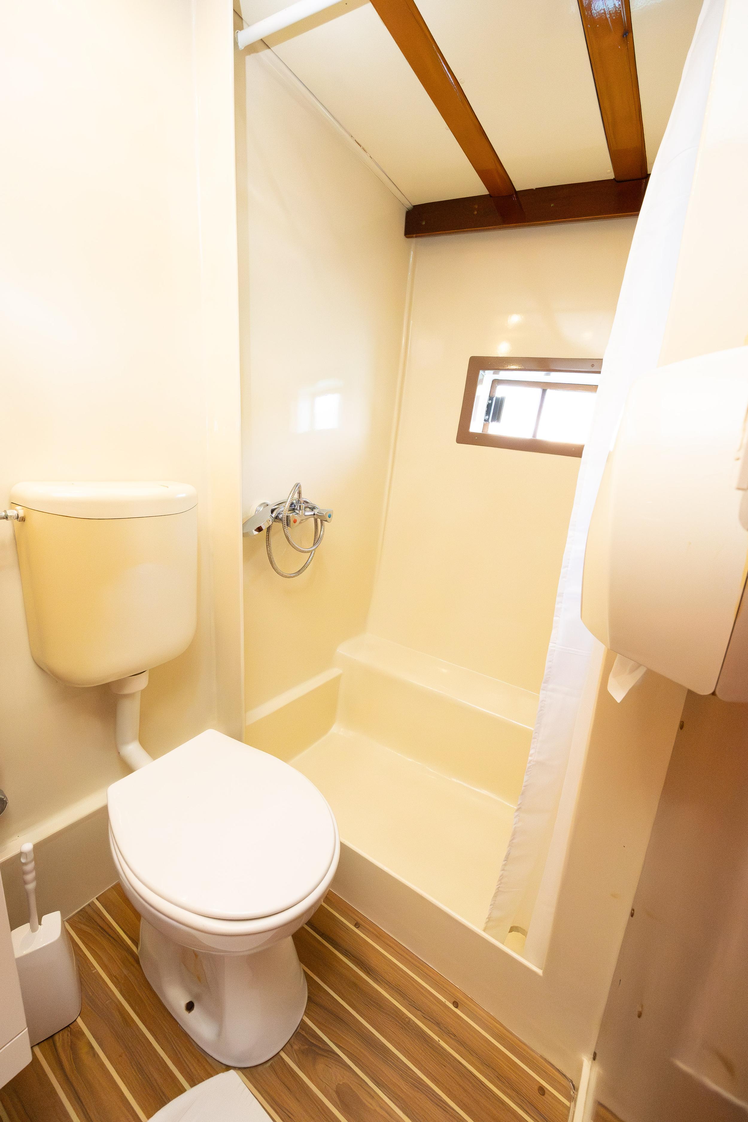 Gulet cabin en-suite bathroom with white toilet, open shower area, and teak-style floor